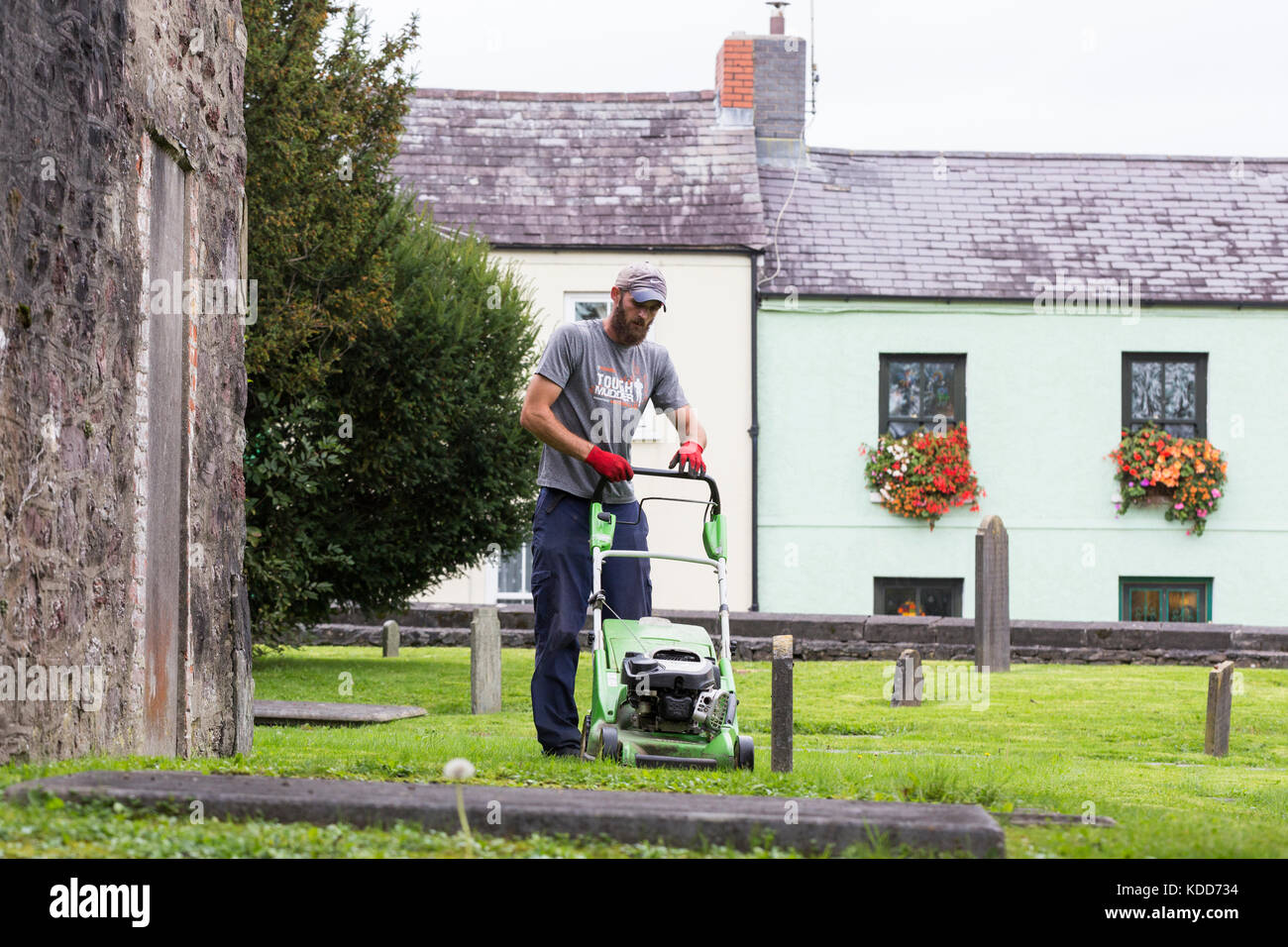 Man mowing grass with lawn mower in church graveyard Stock Photo Alamy