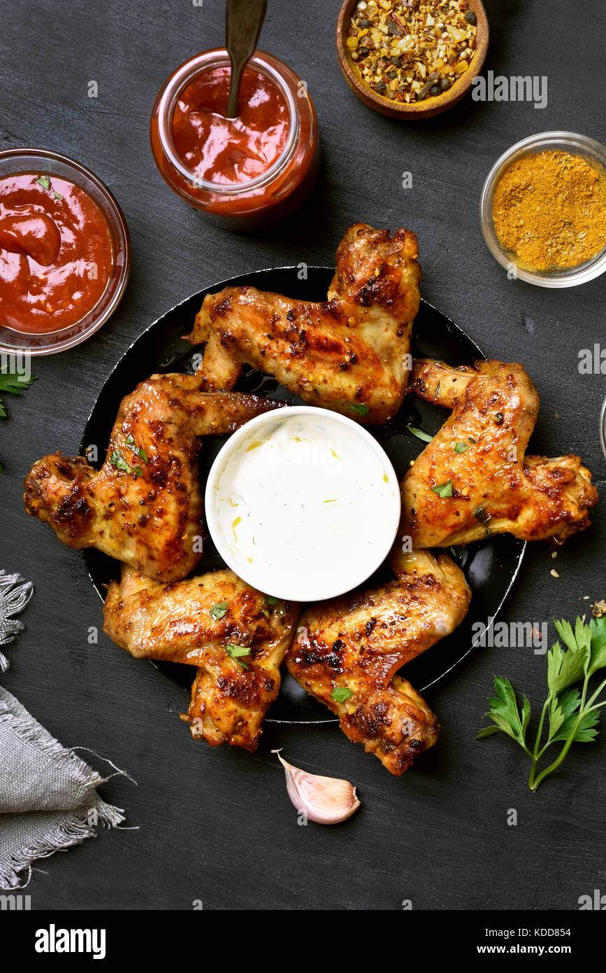 Barbecue chicken wings with sauce on dark background, top view Stock