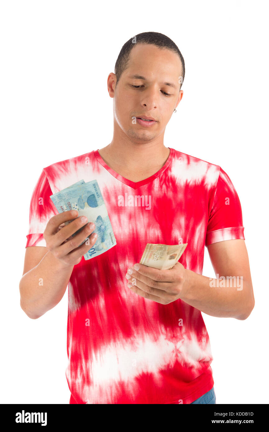 Man holds paper banknotes. Currency: Real. Young latin american man wearing white and red shirt. White background. Stock Photo