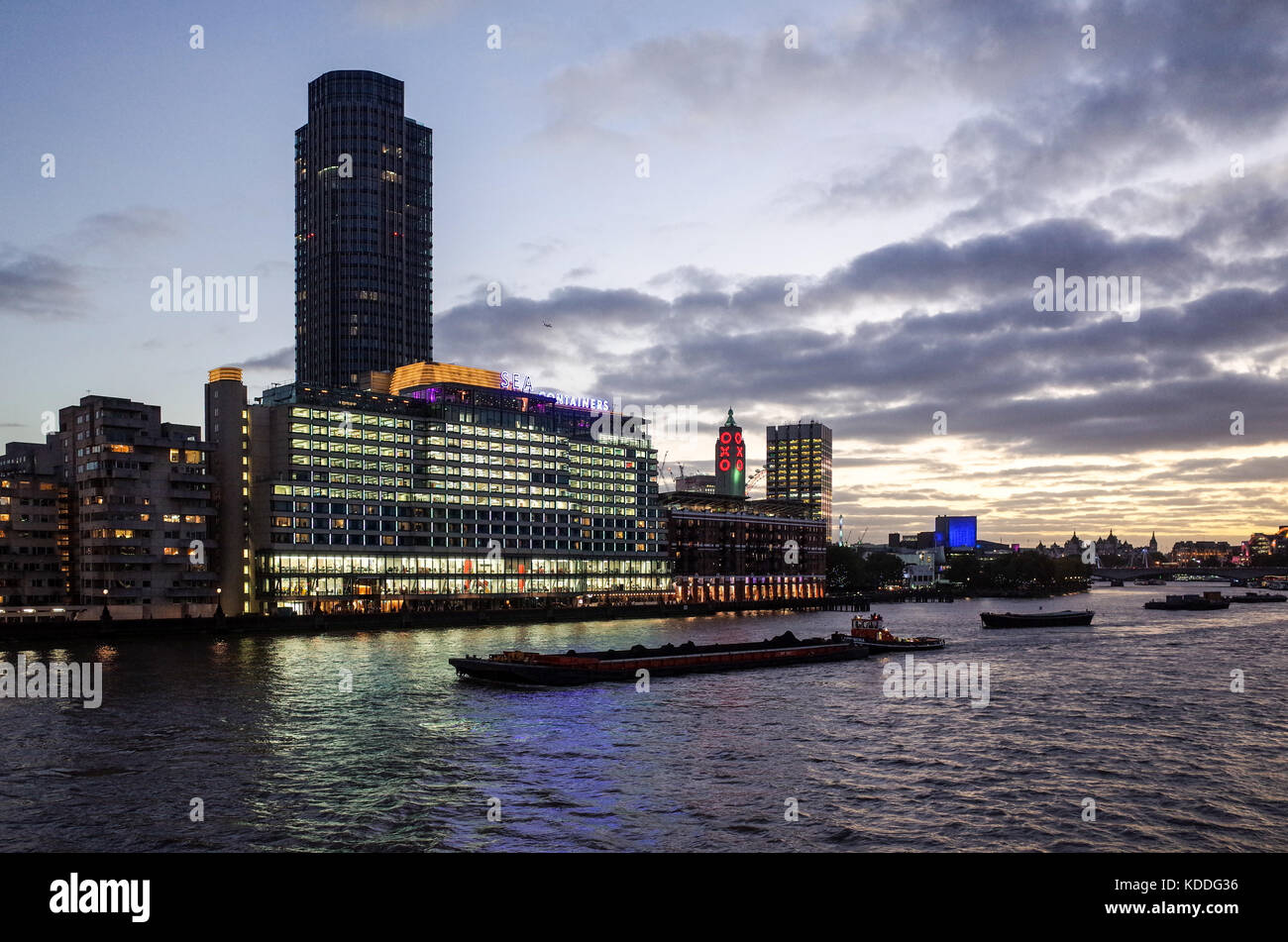 London Southbank Skyline - Southbank Cityscape - River Thames Traffic passes Sea Containers House complex and the Oxo Tower at Dusk Stock Photo
