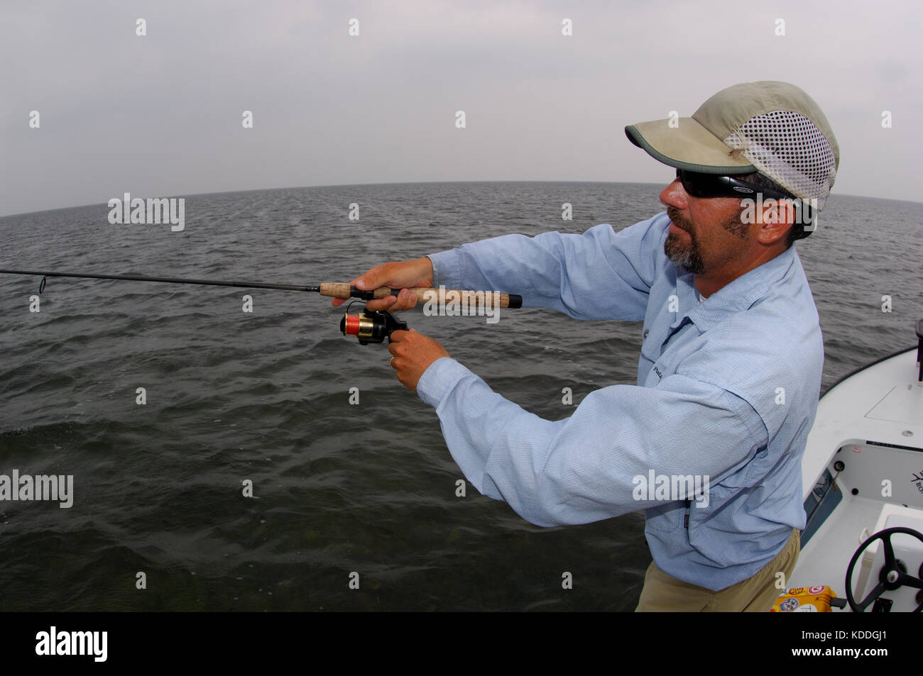 A fisherman casts a spinning rod for redfish while fishing on the shallow flats of the Laguna Madre in South Texas Stock Photo