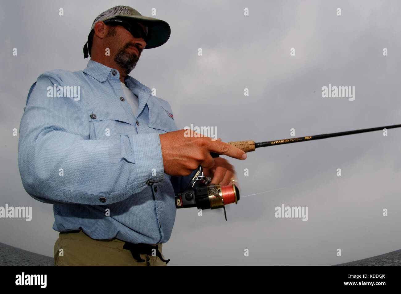 A fisherman casts a spinning rod for redfish while fishing on the shallow flats of the Laguna Madre in South Texas Stock Photo