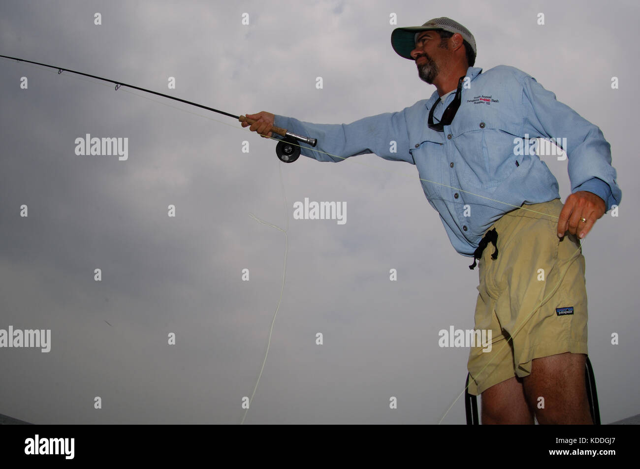 A fisherman casts a fly rod for redfish while fishing on the shallow flats of the Laguna Madre in South Texas Stock Photo