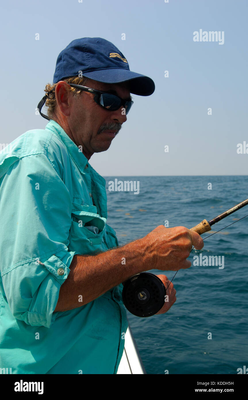 A fly fisherman fights a big fish while fishing offshore from Freeport, Texas Stock Photo