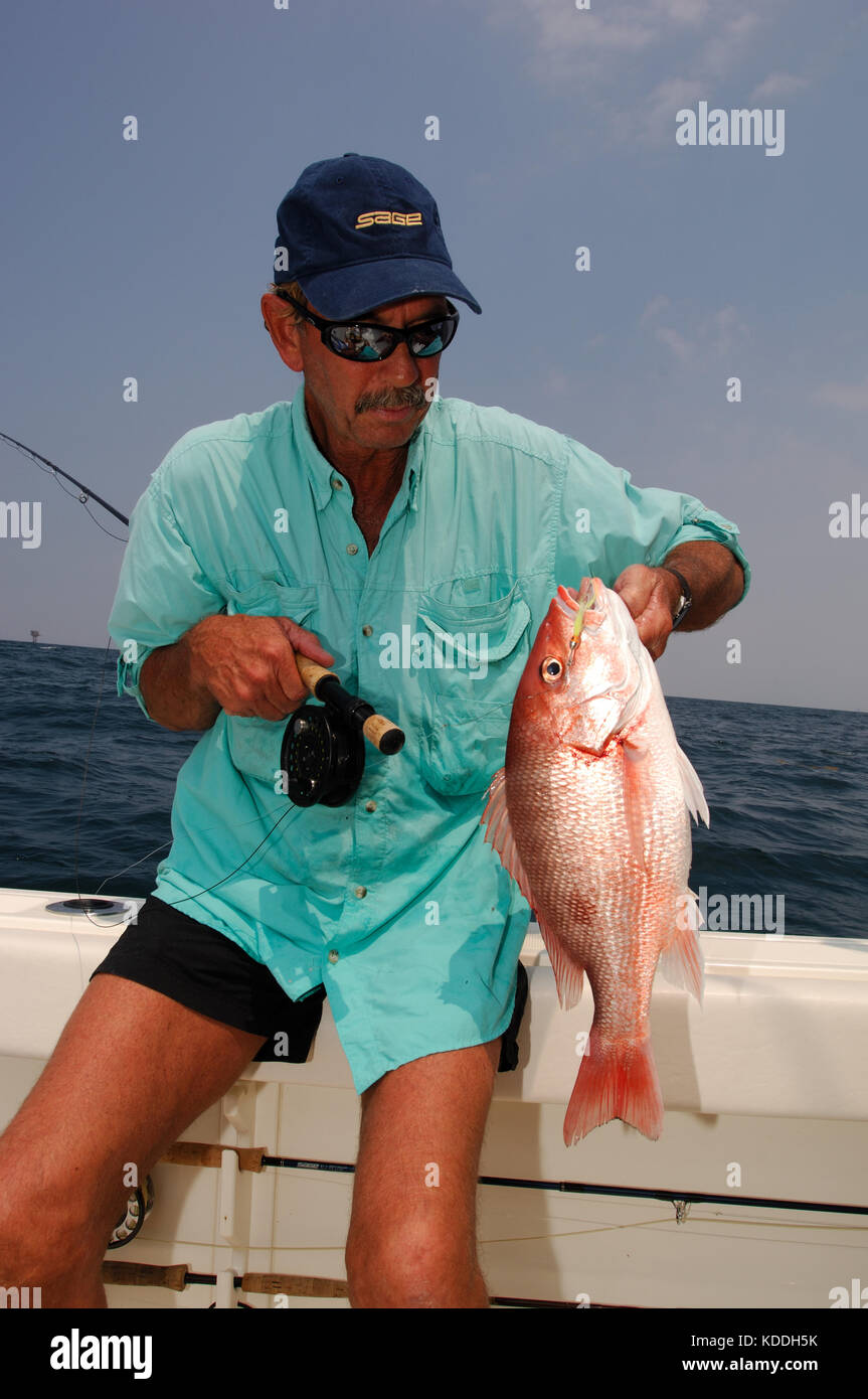 A fly fisherman holds a red snapper caught while fly fishing offshore from Freeport Texas Stock Photo