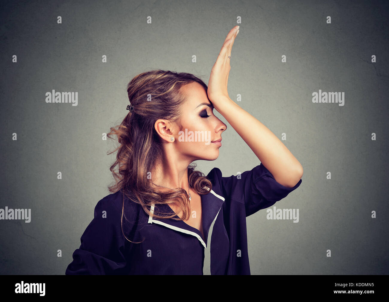 Regrets wrong doing. Sad woman, slapping hand on head having duh moment isolated on gray background. Negative human emotion feeling, body language Stock Photo