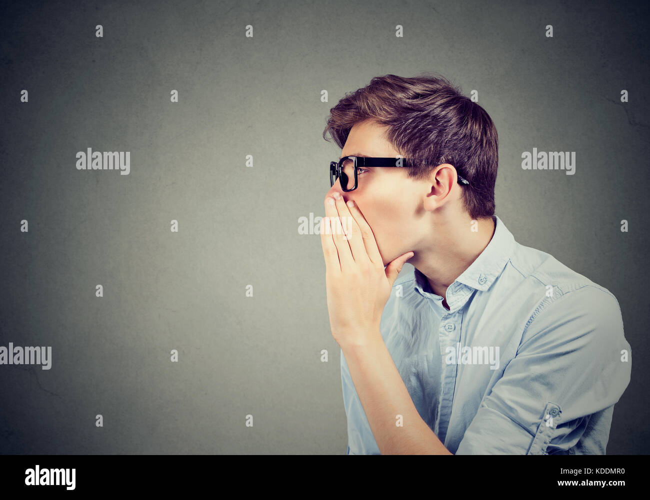 I have a secret to tell you. Man whispering a gossip isolated on gray background Stock Photo