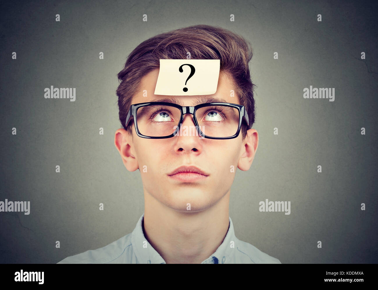 thinking man with question mark looking up on gray wall background Stock Photo