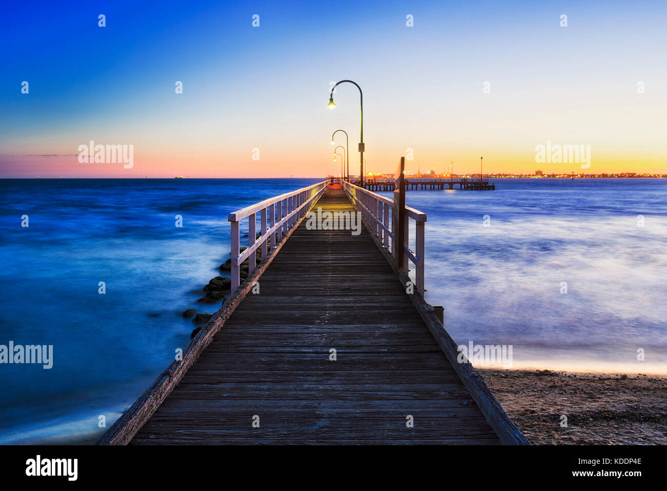 Bright warm over sea horizon at Port Melbourne beach wooden jetty