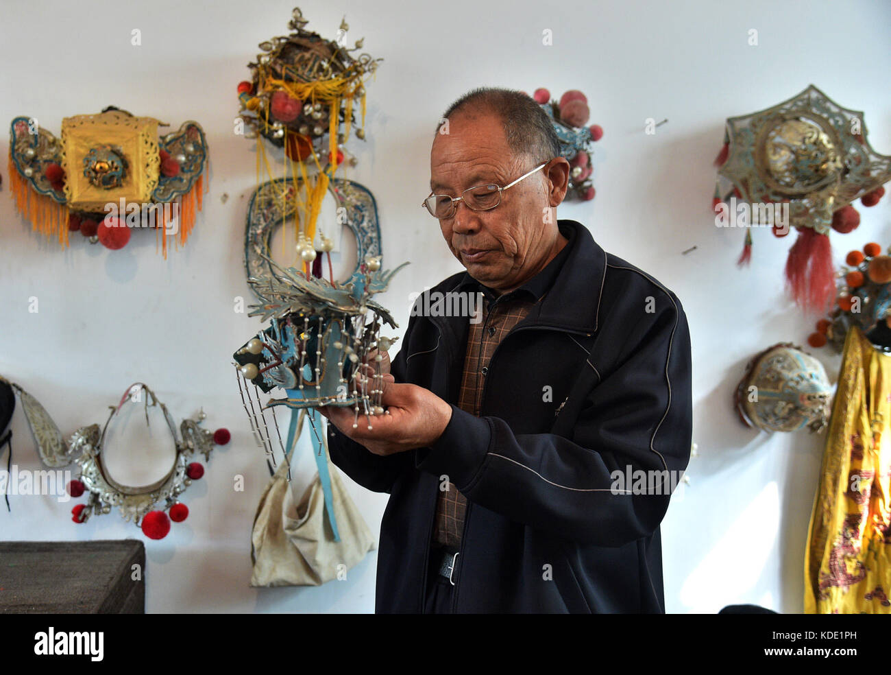 Shijiazhuang, China's Hebei Province. 12th Oct, 2017. Zhang Gengmin, head of Tongle Sixian Troupe, checks the headwear used for the performance of Sixian, a local opera, at Nanke Village of Shijiazhuang City, capital of north China's Hebei Province, Oct. 12, 2017. Actually all actors of the troupe are local villagers, who practise and perform the opera during slack seasons in farming. Credit: Qie Lei/Xinhua/Alamy Live News Stock Photo