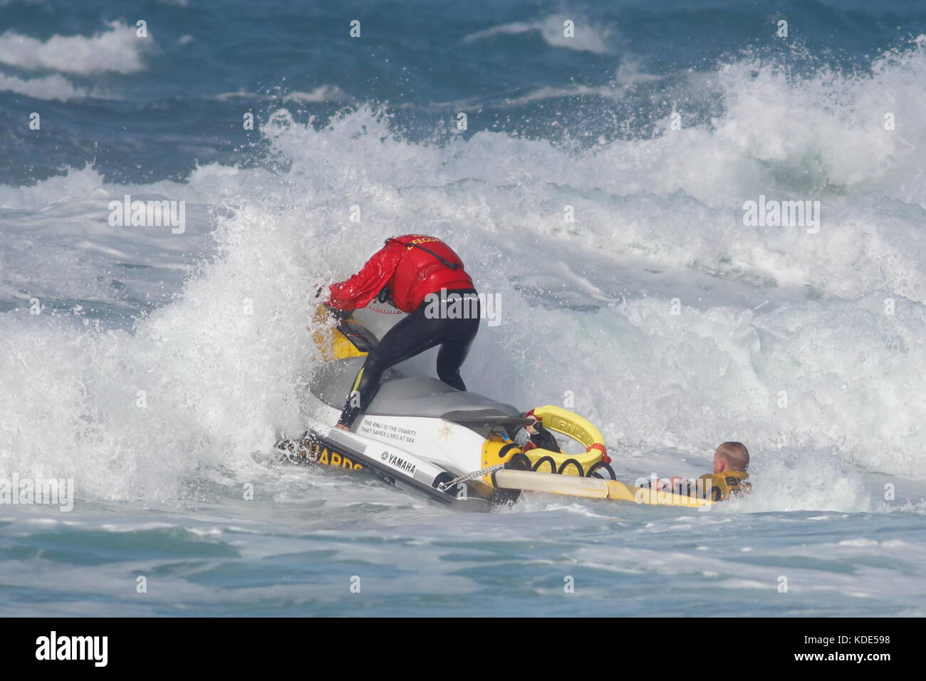 Fistral Beach, Newquay, Cornwall, UK. 13th October, 2017. Surfers take part in Day 1 heats of the British University and College Sports Surfing Competition. A surfer is helped by the RNLI away from the rocks on the north side of the beach. Stock Photo