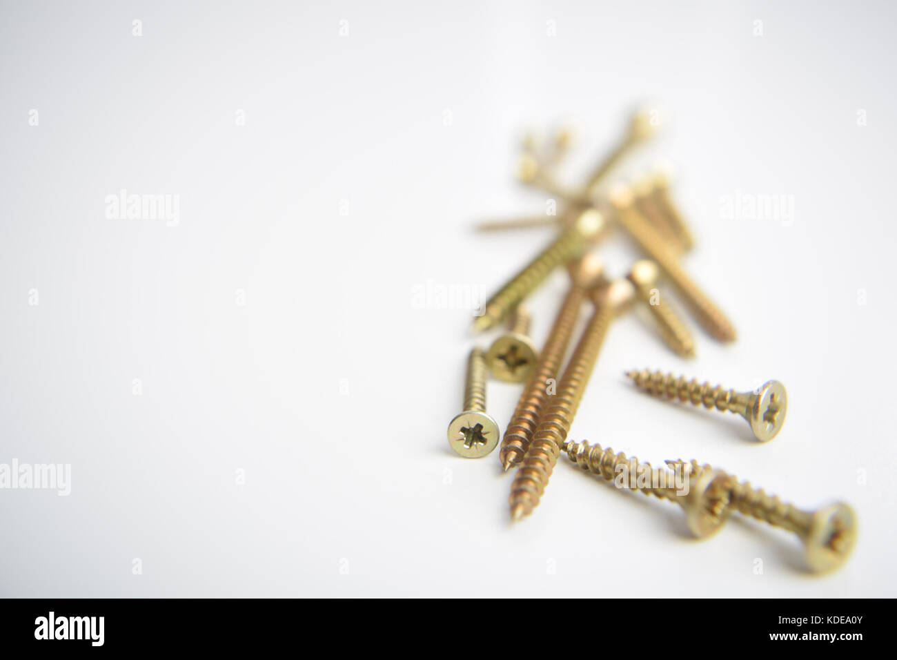 Pile of brass screws placed on a white background with shallow depth of field Stock Photo
