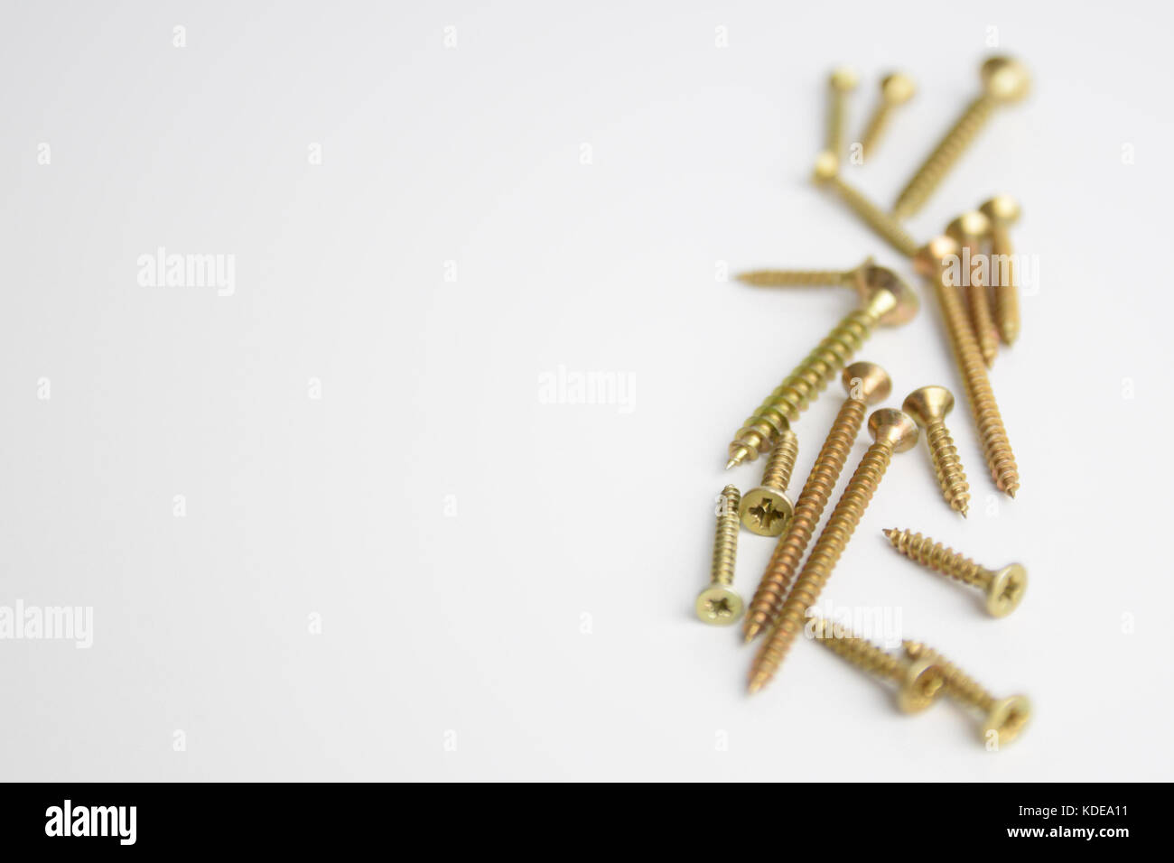 Pile of brass screws placed on a white background with shallow depth of field Stock Photo
