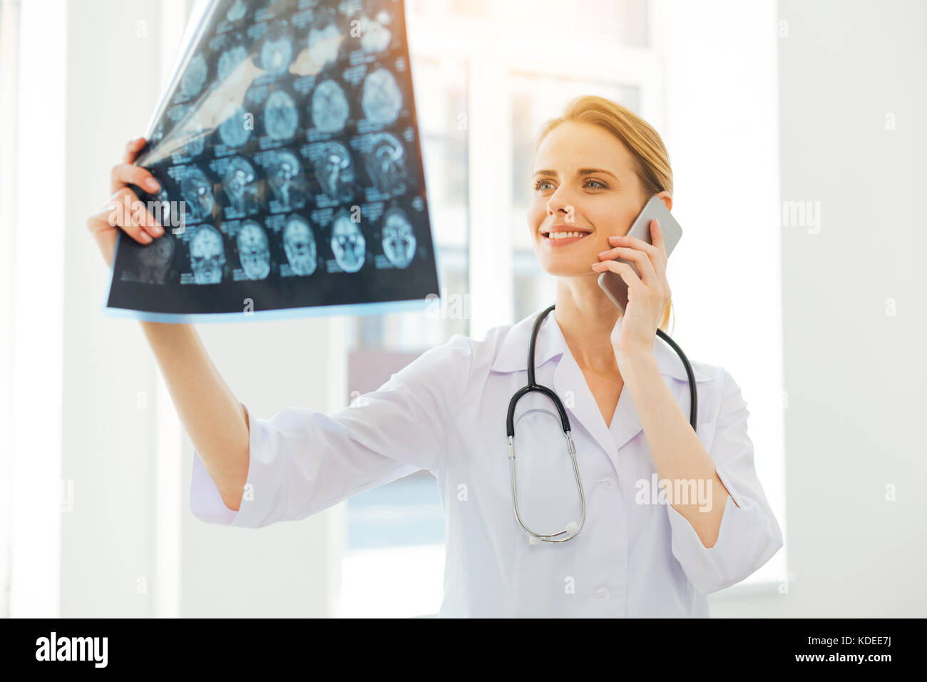 Confident female radiologist smiling while looking at MRI scan image Stock Photo