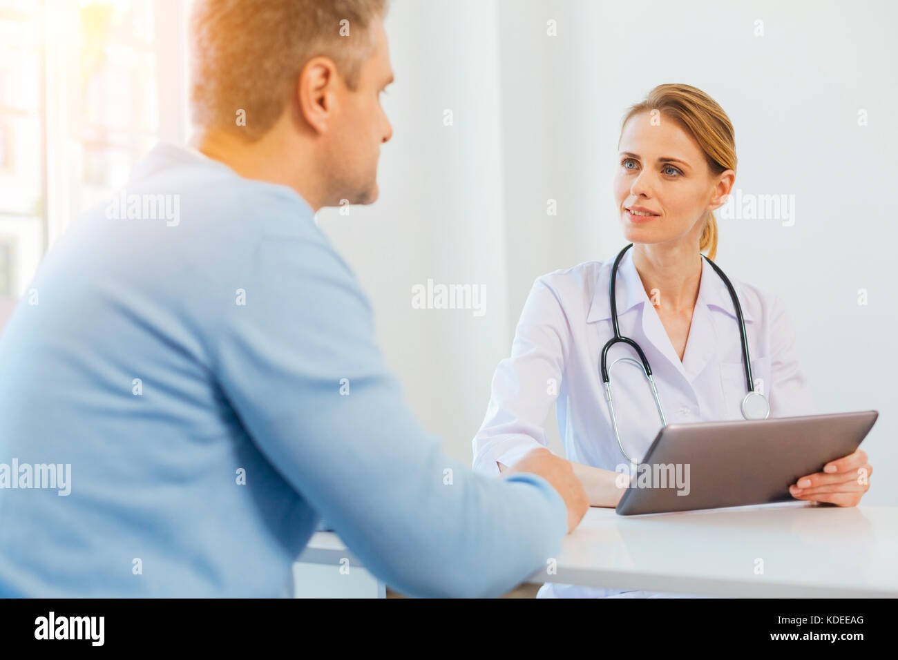 Mindful female doctor listening to patient Stock Photo