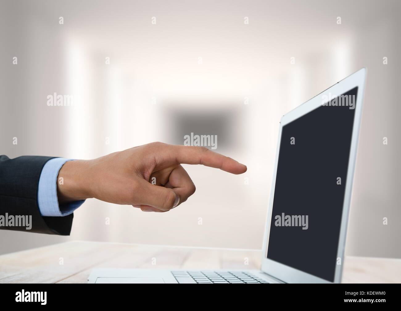 Digital composite of Hand pointing at laptop with bright background ...