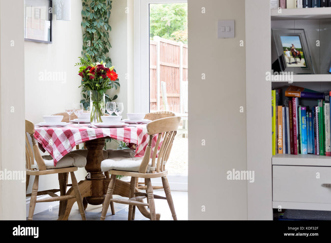 A small dining table with tablecloth set for lunch in a domestic dining room. Stock Photo
