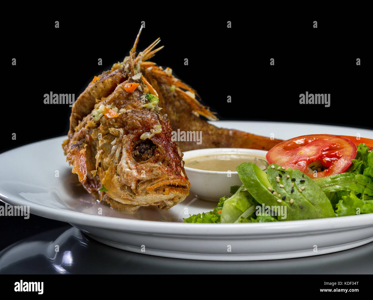 whole fish deep fried and served with a side salad Stock Photo