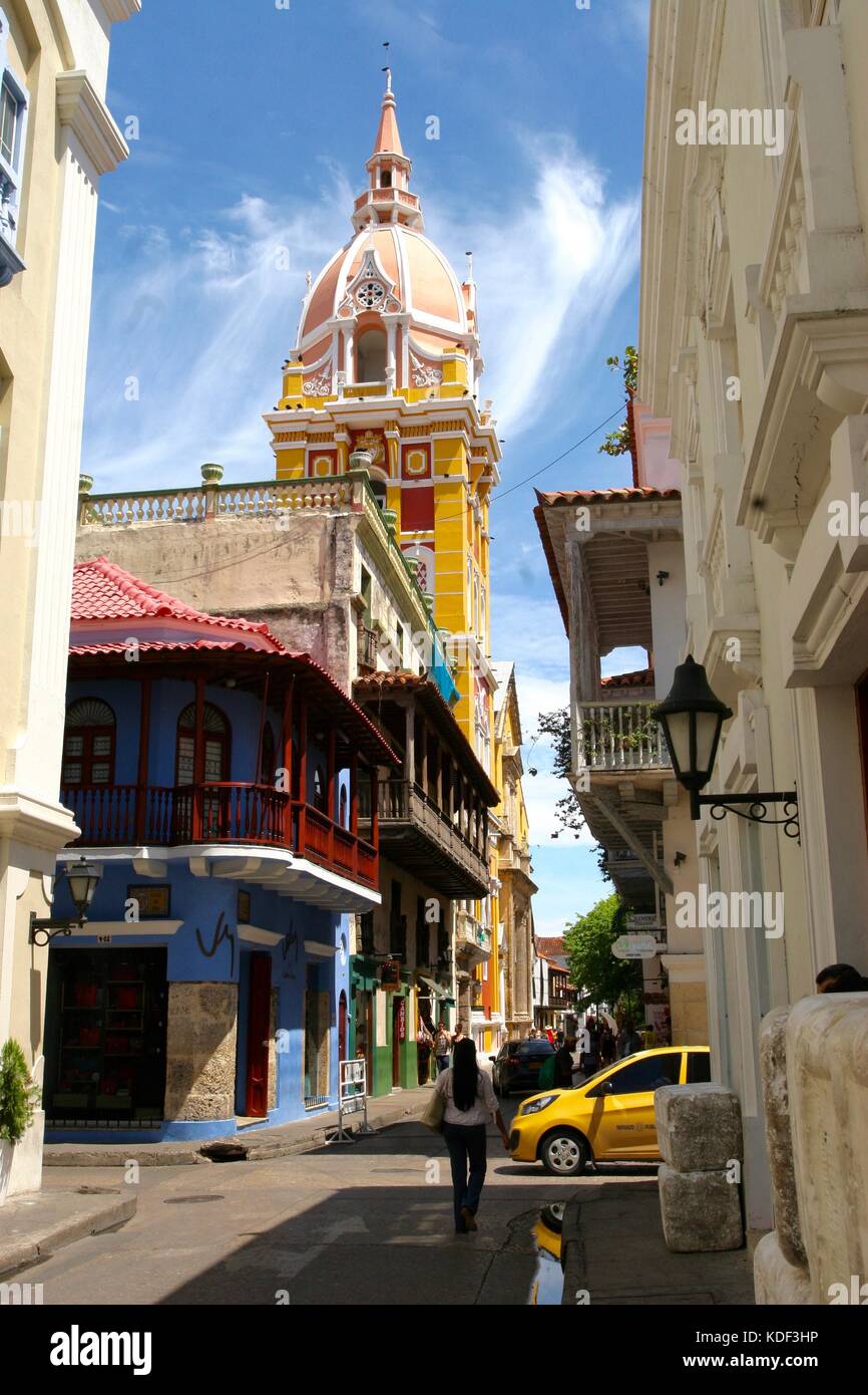 A woman walks down a street in Cartagena, Colombia with the Metropolitan Cathedral Basilica of Saint Catherine of Alexandria in the background Stock Photo