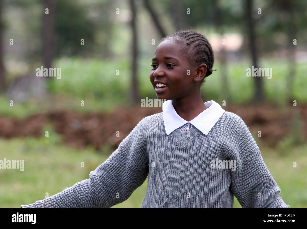 A young african girl in a school uniform smiles as she plays outside of her school in Njabini, Kenya Stock Photo