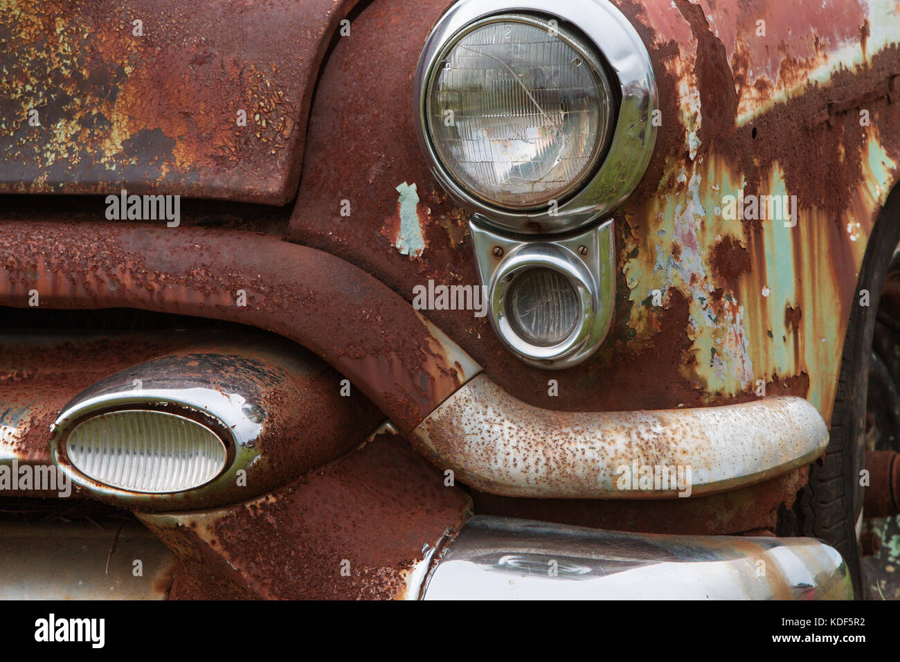 Cracked headlight and chipped paint on old rusted junkyard car Stock