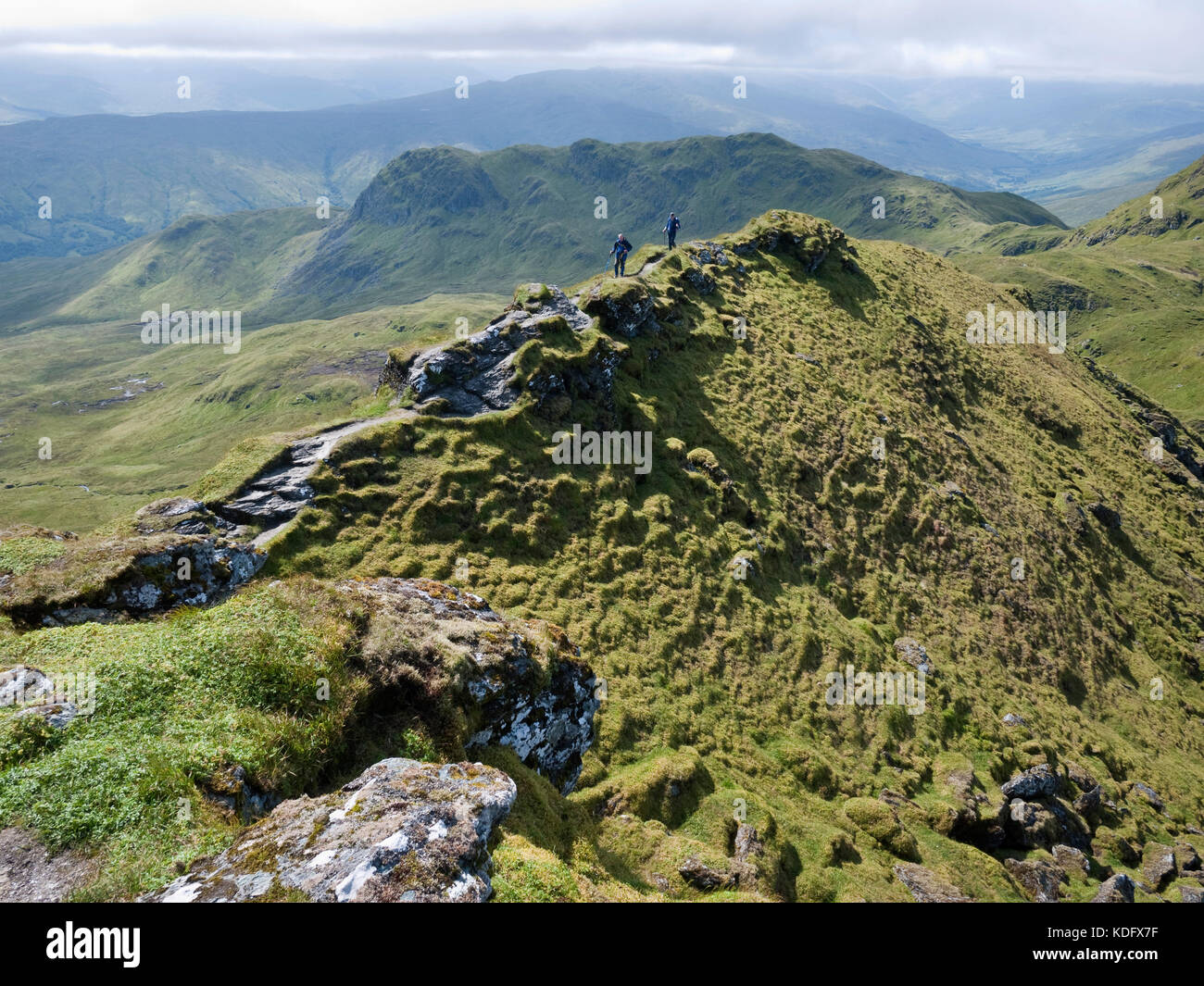Hikers crossing the narrow section of ridge on Meall Garbh, on the Tarmachan Ridge Stock Photo