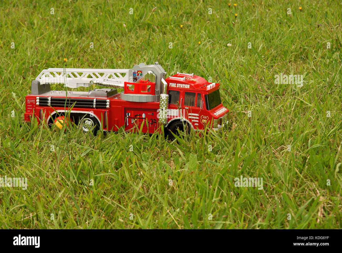 A childs abandoned toy fire engine left outside on a grassy lawn Stock Photo