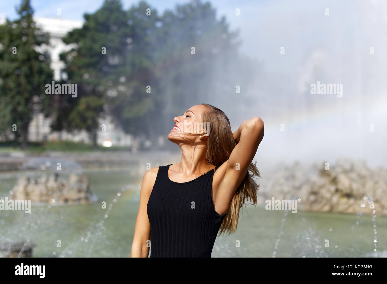 Young carefree woman looking away at park fountain outdoor Stock Photo