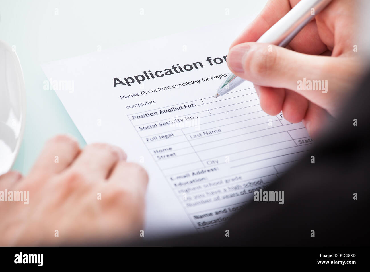 Close-up Of Man's Hand Filling Application For Employment Stock Photo