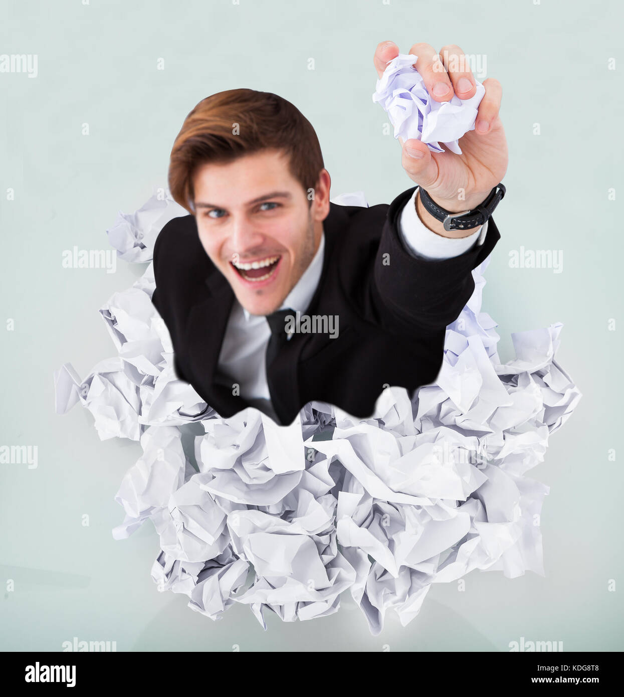 Person Under Pile Of Crumpled Paper With Hand Holding A Paper Stock Photo