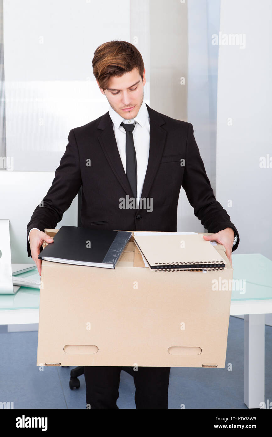 Portrait Of A Young Businessman Carrying Box At His Workplace Stock Photo