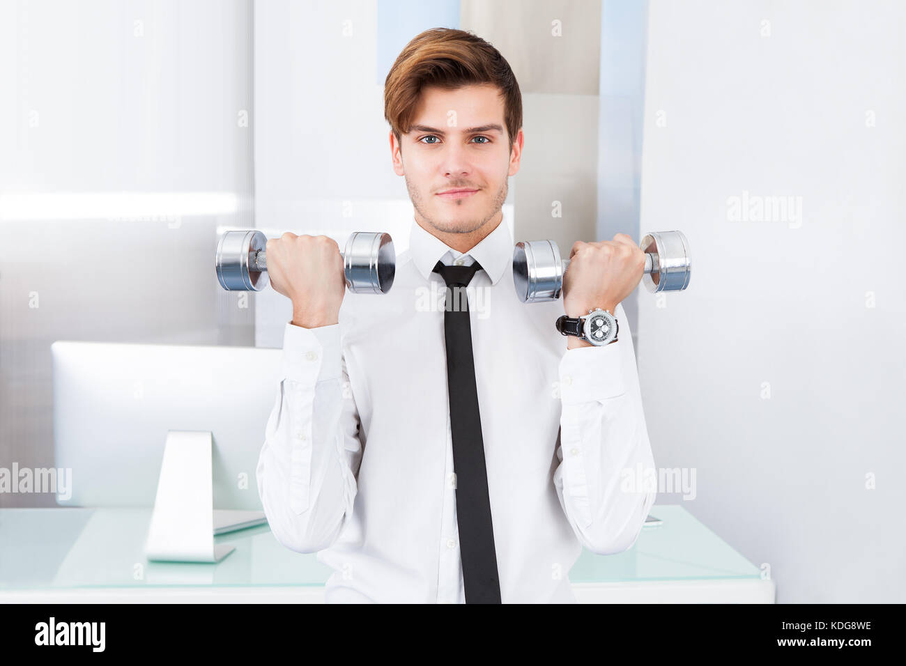 Handsome Young Businessman Exercising With Dumbbells At Office Stock Photo