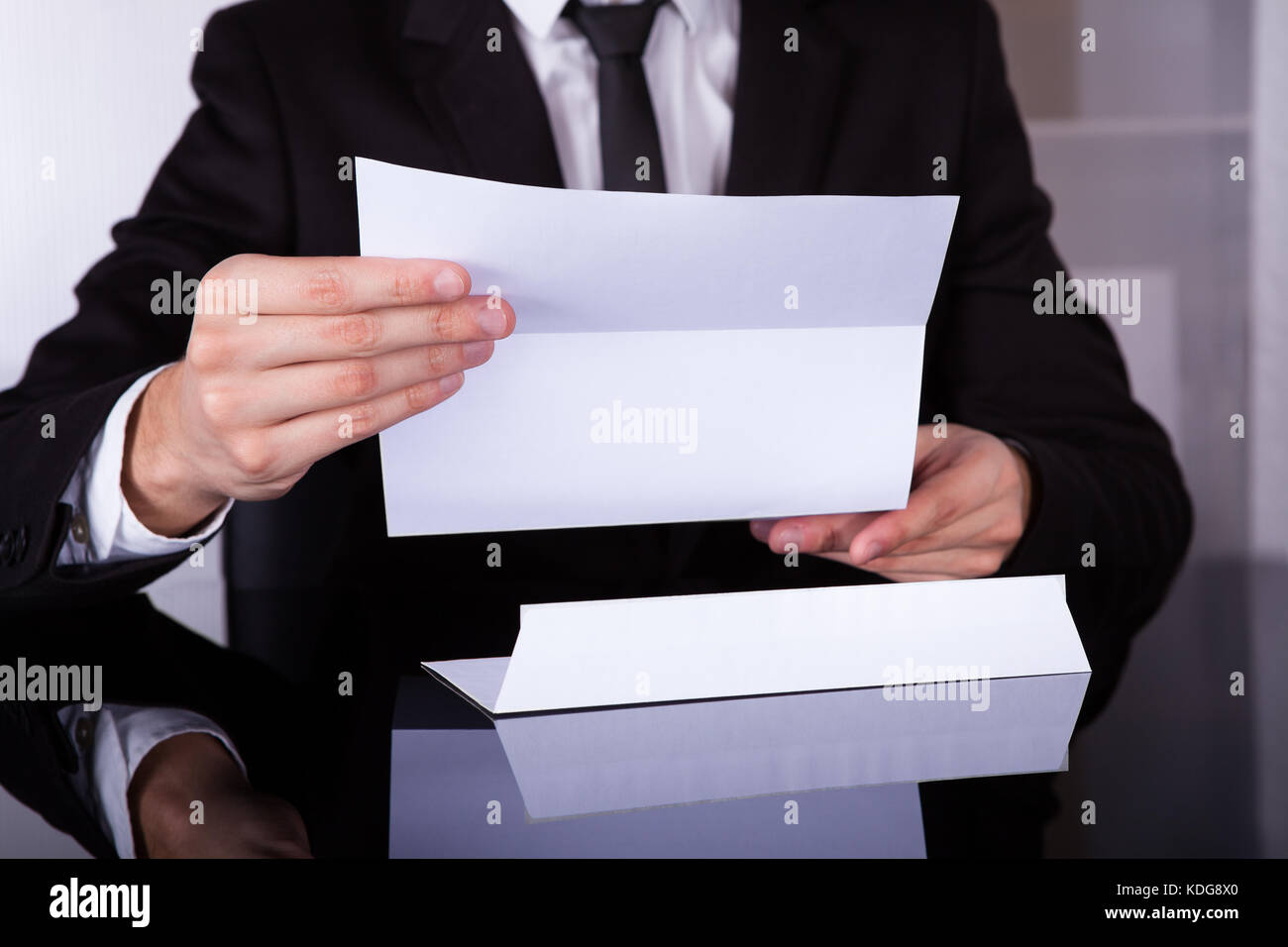 Close-up Of Businessman Holding Document At Desk Stock Photo