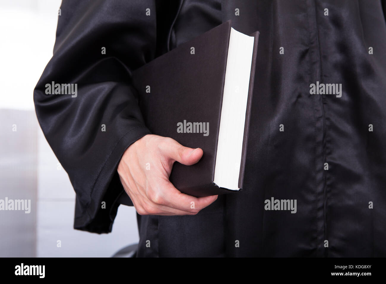 Close-up Of Male Judge In Robe Holding Law Book Stock Photo