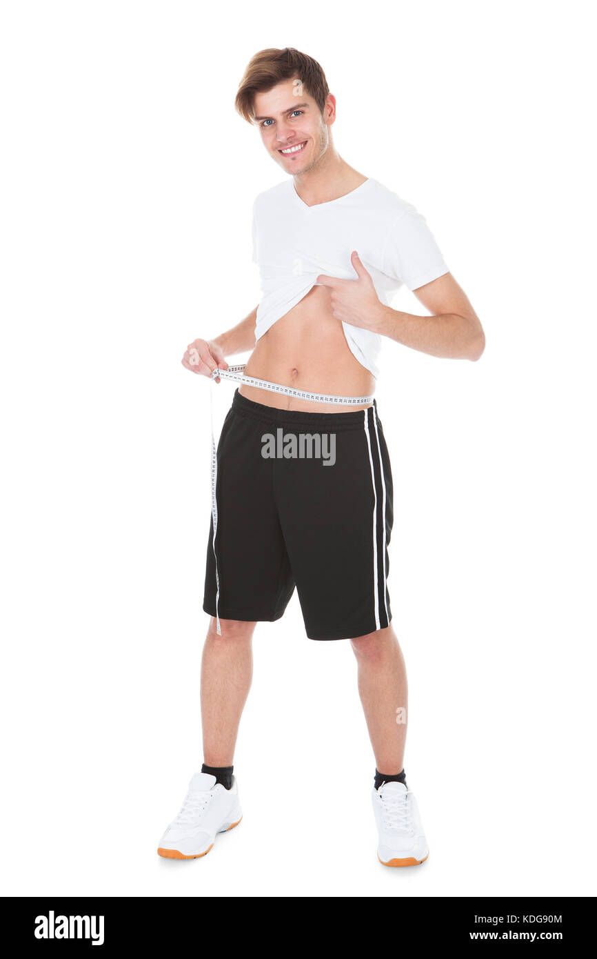 Portrait Of A Happy Young Man Measuring His Waistline Stock Photo