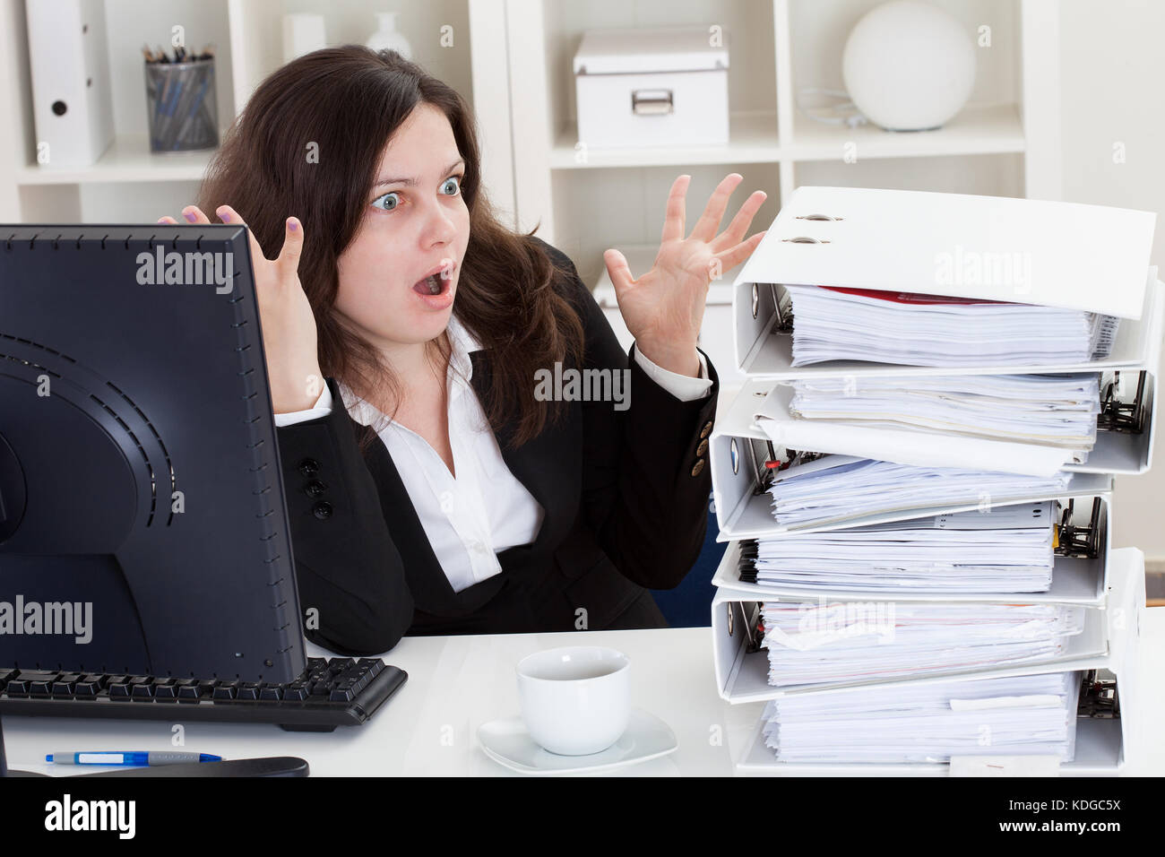 Businesswoman Shocked By Watching Stack Of Folders In Office Stock Photo