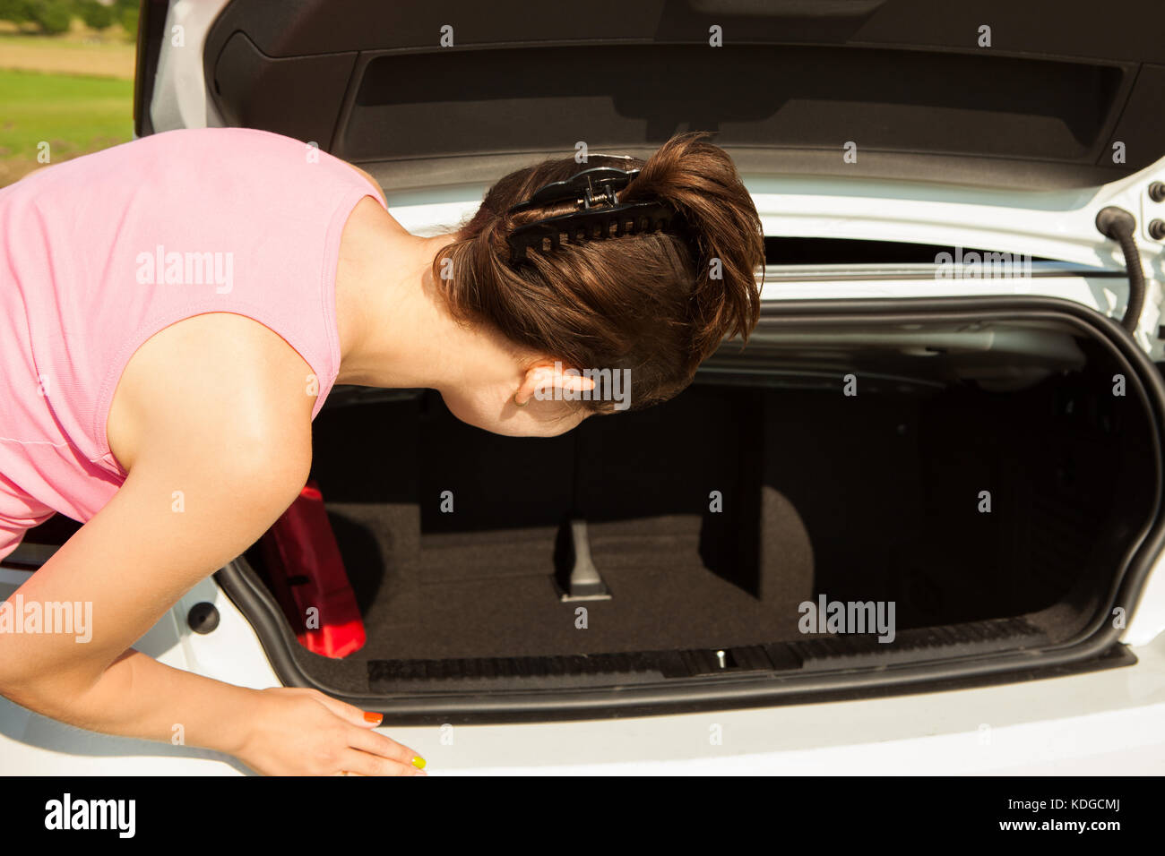 Young Woman Looking In The Car Trunk Stock Photo