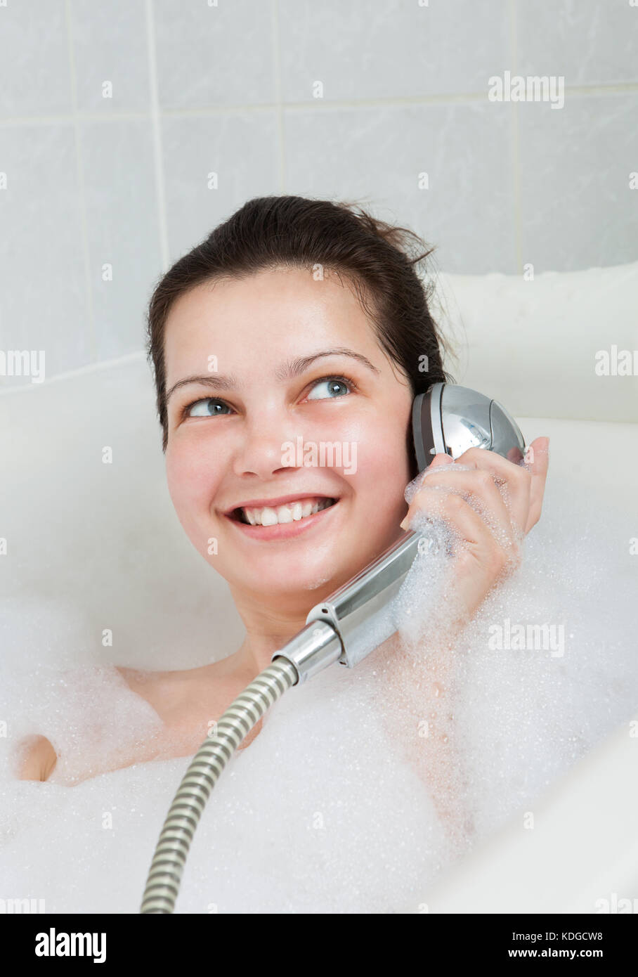 Portrait of a woman bathing in bathtub and holding shower Stock Photo