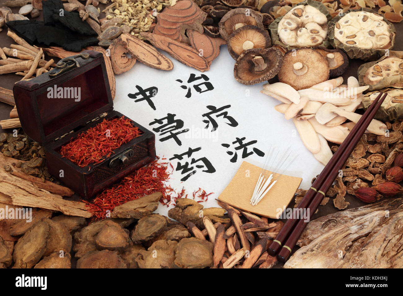 Chinese herbal medicine with acupuncture needles and a selection of herbs with safflower in a wooden ox and calligraphy script on rice paper. Stock Photo