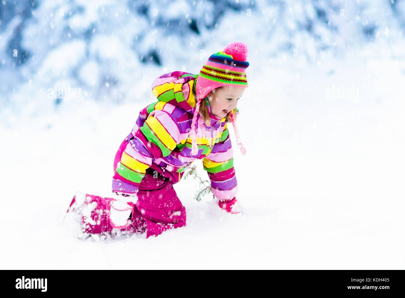 Child playing with snow in winter. Little girl in colorful jacket and ...