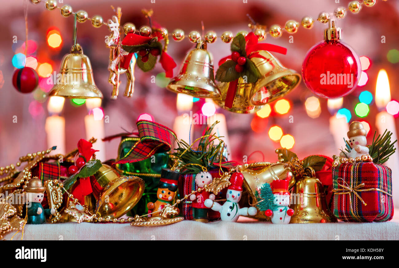 Christmas tree decorative miniatures, toys, props, showing bells, gifts and presents, snowman and christmas bokeh lights in the background and candles Stock Photo