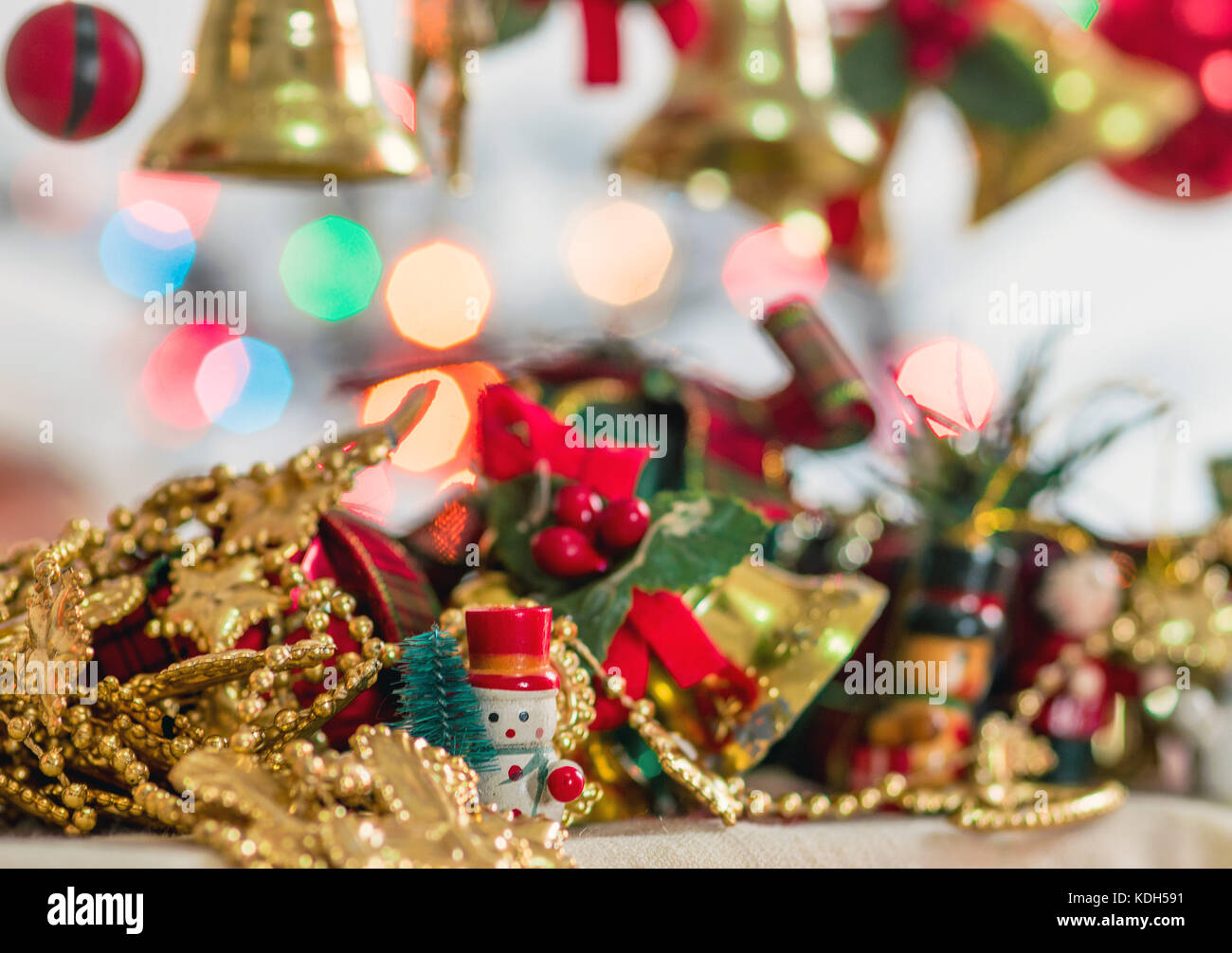 Christmas tree decorative miniatures, toys and props, showing bells, gifts and presents, snowman and christmas bokeh lights in the background Stock Photo