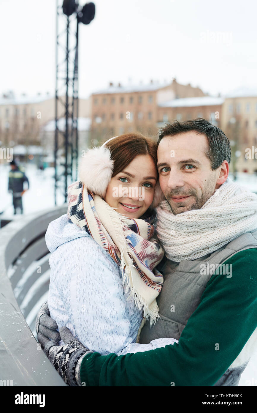 Young couple in winterwear standing in embrace in urban environment Stock Photo