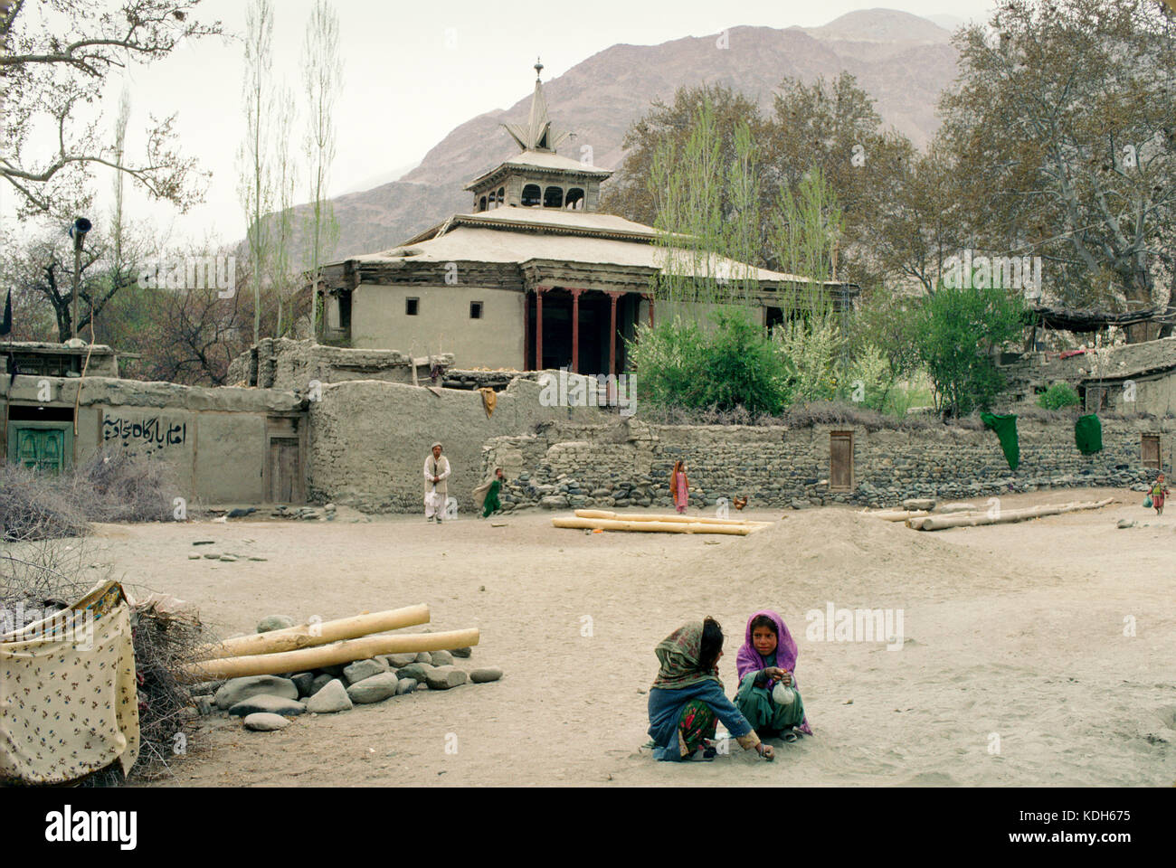 Upper Indus Valley Pakistan, 1990; Children play in  Shigar village, with the mosque  and mountains behind. Stock Photo