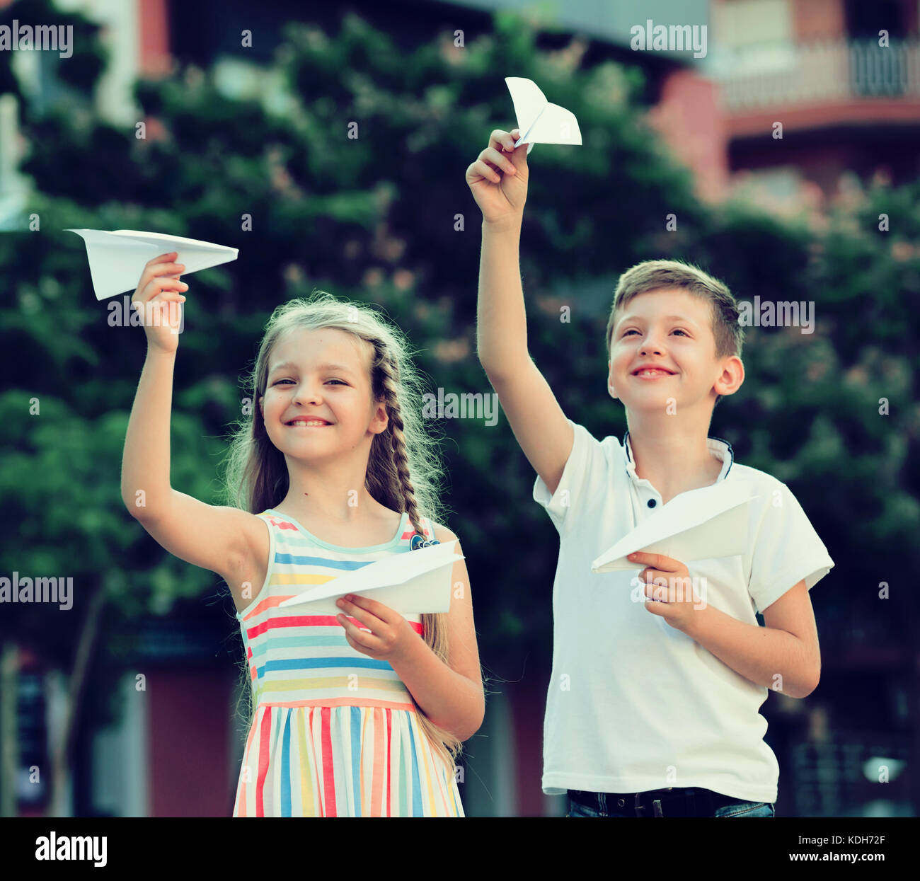 Two smiling kids playing with flying paper planes outdoors Stock Photo ...