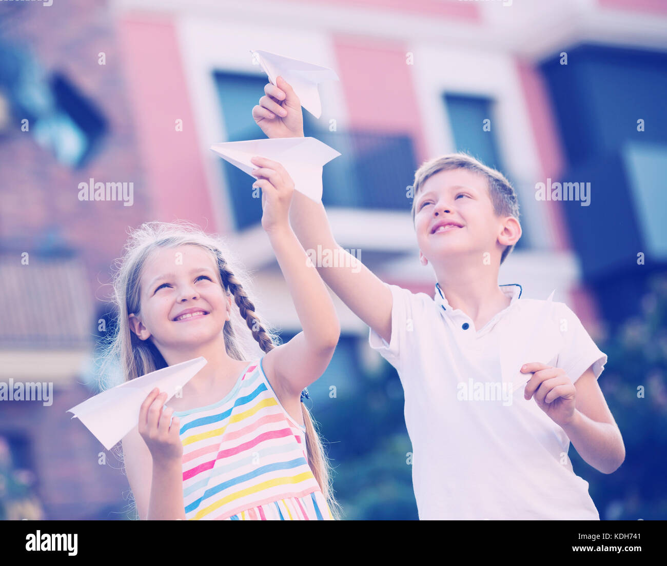Two smiling kids playing with flying paper planes outdoors Stock Photo ...