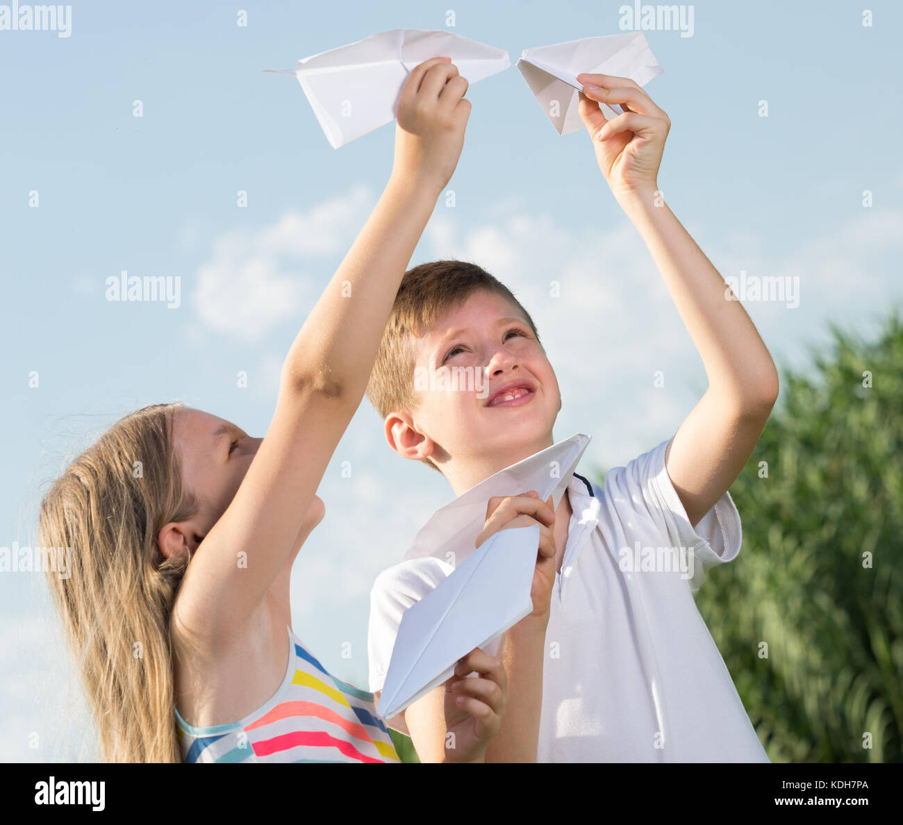 Two happy smiling kids playing with flying paper planes outdoors Stock ...