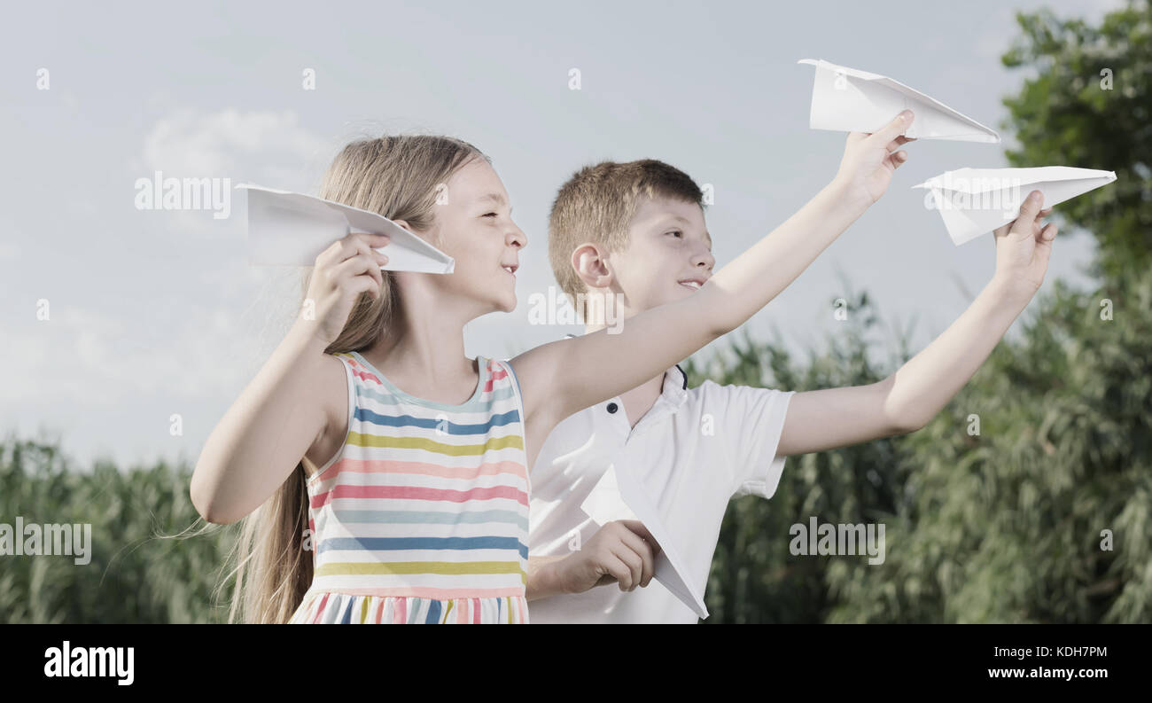 two positive kids playing with simple paper planes on sunny day Stock ...