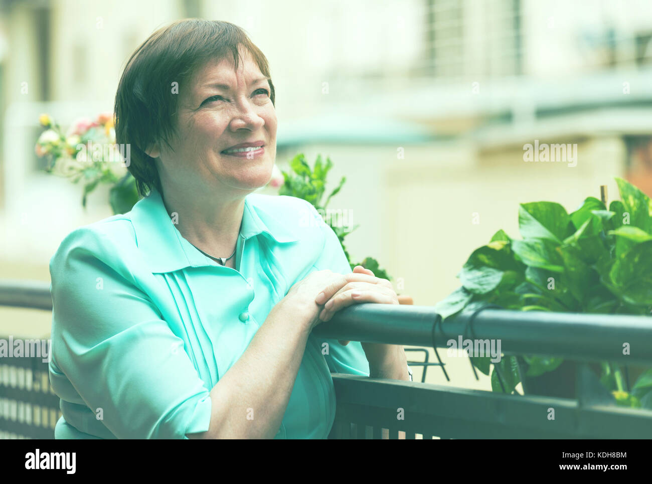Cheerful senior woman sitting on terrace and smiling Stock Photo - Alamy