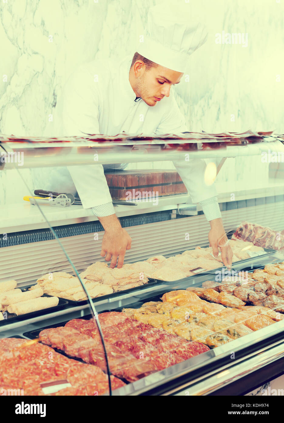 concentrated young seller at butcher store offering fresh products Stock Photo